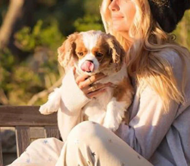 Woman holding a dog outdoors with a blurred natural background